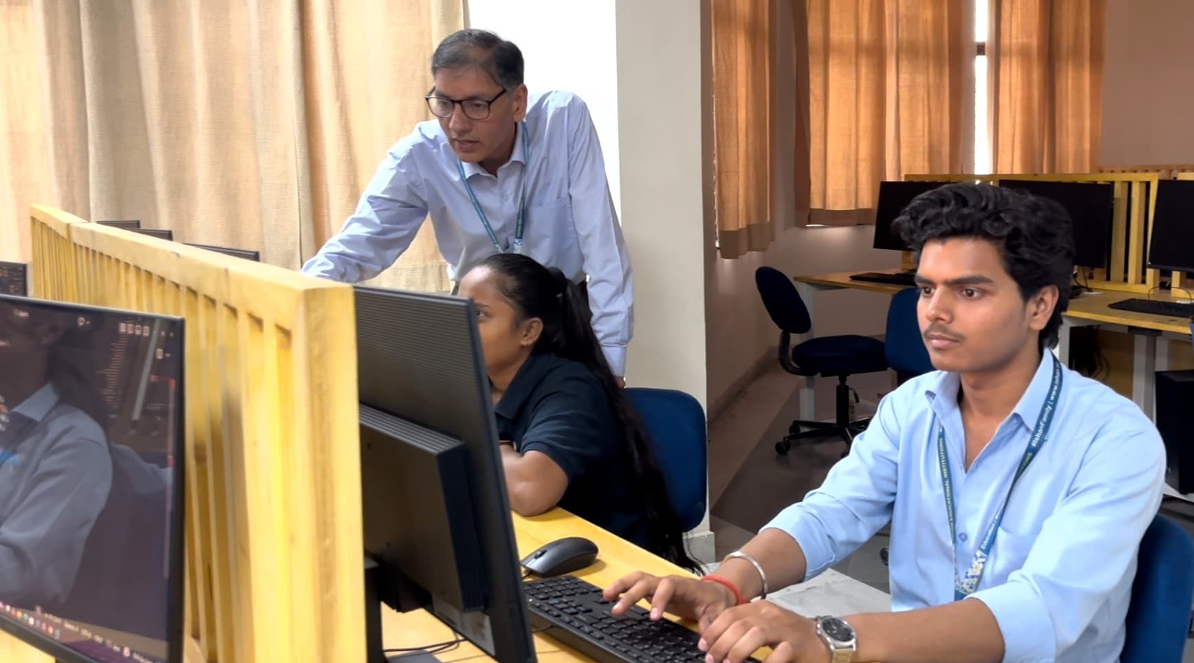 Faculty guiding students at computers